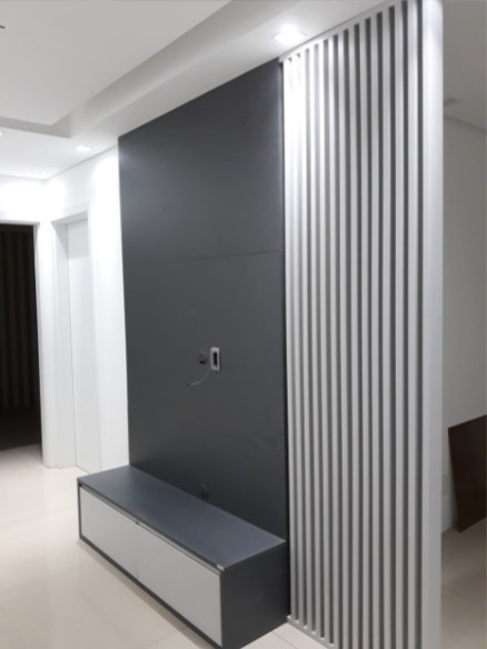 Sala de estar com painel para TV em grafite, ripado em tom claro e rack suspenso